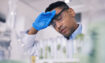 Man wiping sweat off his face in a laboratory due to summer heat