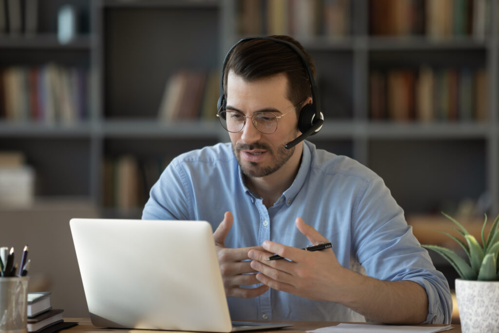 Ein Mann trägt ein Headset und führt ein virtuelles Gespräch über den Computer