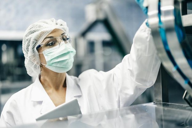 Pharmacy technician reviewing automated temperature monitoring dashboard in sterile compounding cleanroom